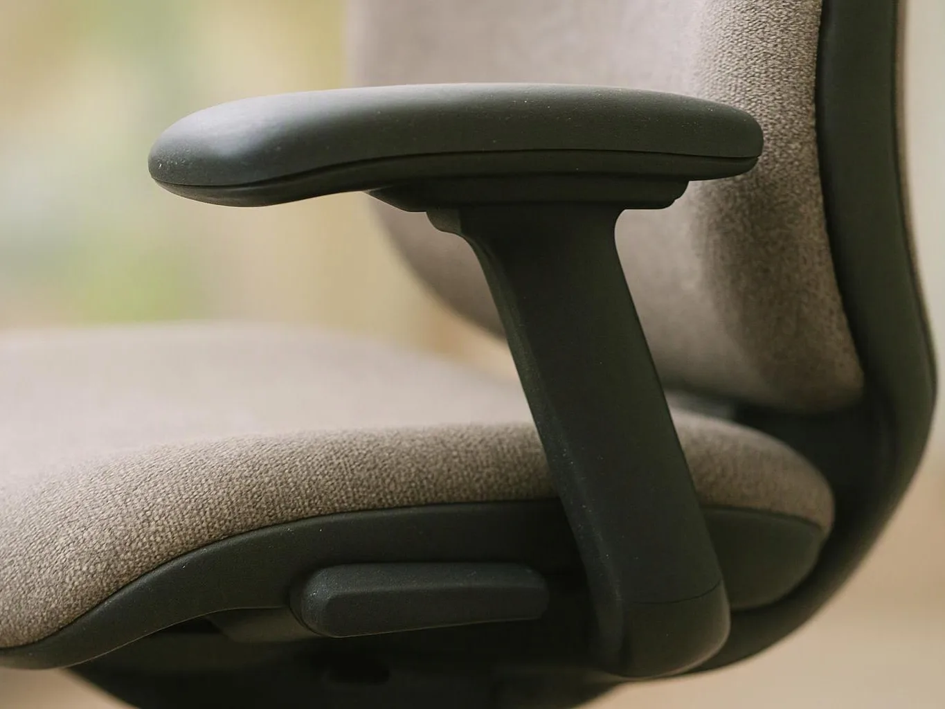 Close-up of a gray office chair showing the armrest, seat cushion, and adjustment lever